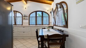 Una cucina con un tavolo da pranzo, sedie, un frigorifero e ampie finestre ad arco.