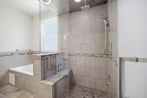 A bathroom with a bathtub, shower, and glass-enclosed shower area. - Hillside Hyde Park Home 4bdr (Cincinnati)