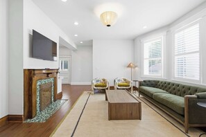 A living room with a fireplace, a sofa, two armchairs, a coffee table, and a television.