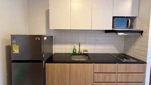 Una cucina con frigorifero, microonde, lavello e pensili in legno.