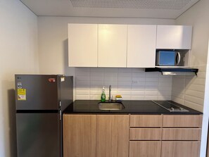 Eine Küche mit Kühlschrank, Mikrowelle, Spüle und Holzschränken.