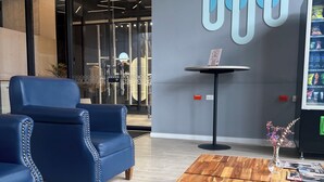 Un interno moderno con divani in pelle blu, un tavolino in legno e un'opera d'arte astratta appesa al muro.