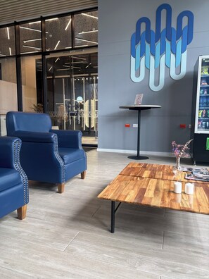 Ein modernes Interieur mit blauen Ledersofas, einem Holztisch und einem an der Wand befestigten, abstrakten Kunstwerk.