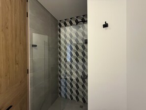 Ein Badezimmer mit Dusche, gefliesten Wänden und einer Holztür.