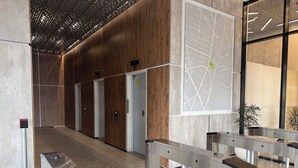 Una hall moderna con pannelli in legno, una mappa appesa al muro e un tornello all'ingresso.