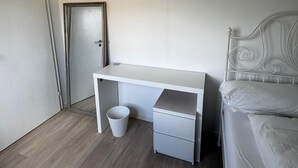 Een slaapkamer met een bed, bureau en een deur.