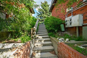 Eine Betontreppe führt zu einem Gebäude mit Backsteinfassade, umgeben von Grünpflanzen.