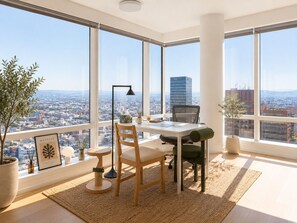 Ein moderner Arbeitsraum mit großem Fenster, Schreibtisch, zwei Stühlen, Topfpflanze und einem gerahmten Bild.