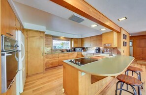 Een moderne keuken met houten kastjes, een centraal eiland, barkrukken en geïntegreerde apparatuur.