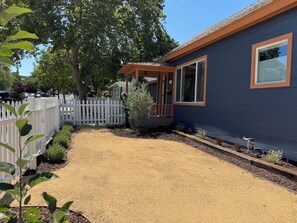Ein Wohnhaus mit überdachter Veranda, umzäuntem Garten und einem Schotterweg.