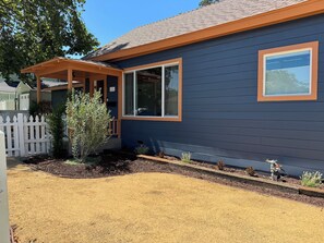 Ein Haus mit überdachter Veranda, umzäunter Garten und gepflegtem Garten.