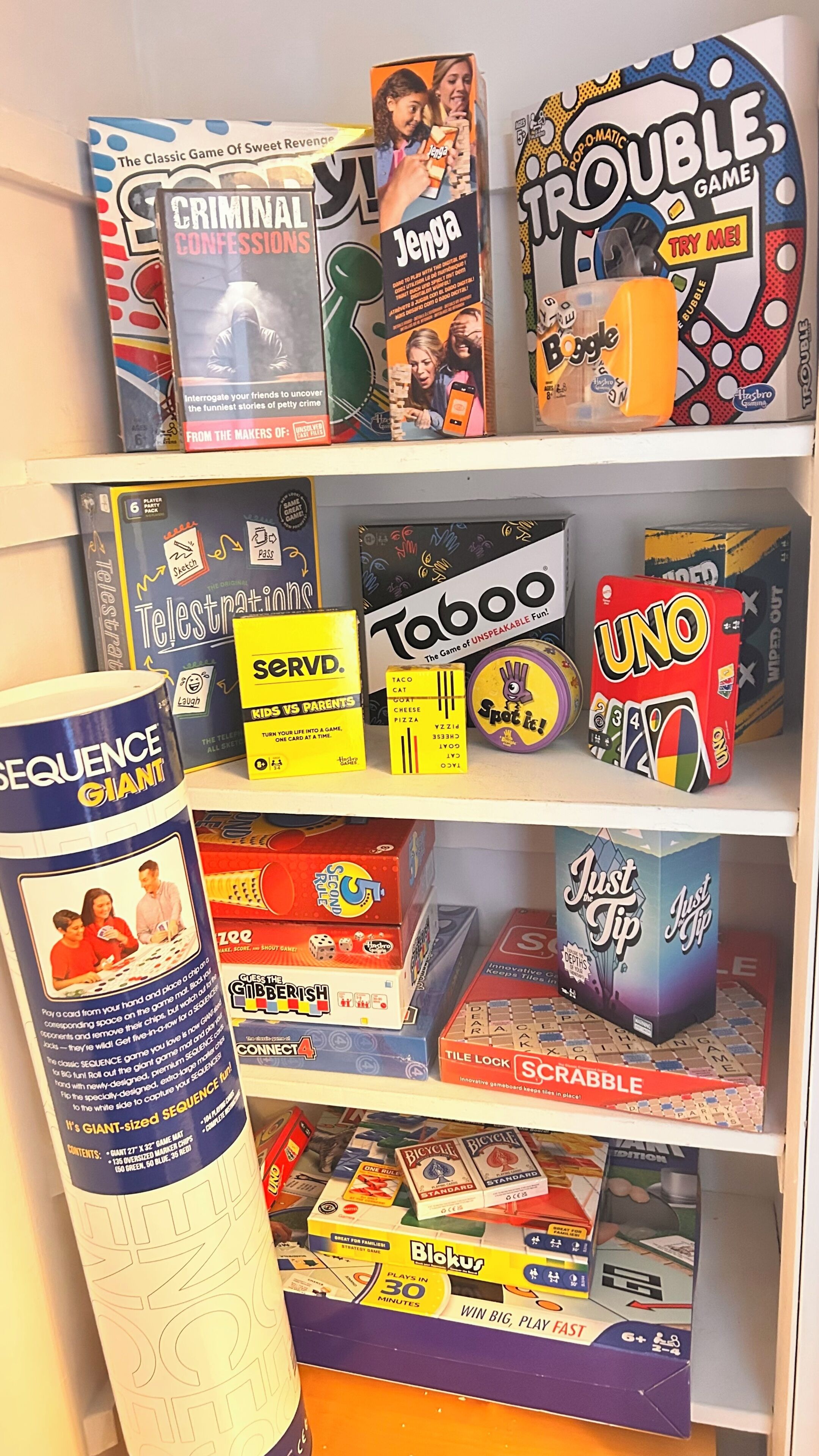 A shelf with various board games, including 'Jenga,' 'Taboo,' and 'Sequence Giant.'