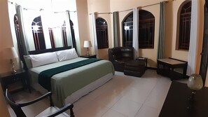Ein Hotelzimmer mit Bett, Sessel, kleinem Tisch und Lampe.