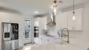 A modern kitchen with white cabinetry, stainless steel appliances, a large island, and pendant lighting. - 30A Escape at 29 Blue Eden Loop (Santa Rosa Beach)