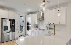 A modern kitchen with white cabinetry, stainless steel appliances, a large island, and pendant lighting. - 30A Escape at 29 Blue Eden Loop (Santa Rosa Beach)