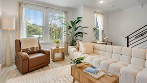 A living room with a sofa, armchair, coffee table, and a staircase. - 30A Escape at 29 Blue Eden Loop (Santa Rosa Beach)
