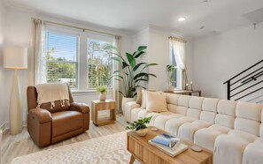 A living room with a sofa, armchair, coffee table, and a staircase. - 30A Escape at 29 Blue Eden Loop (Santa Rosa Beach)