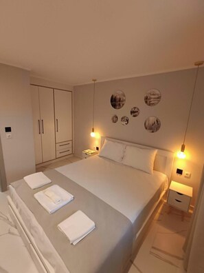 Un dormitorio con cama, mesitas de noche, armario y cuadros en la pared.