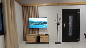 Una sala de estar moderna con televisión, mueble de madera y una mesa de comedor.