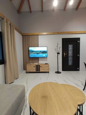 A modern living room with a TV, wooden cabinet, and a dining table.
