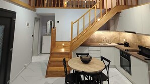 Una amplia cocina estilo loft con una escalera de madera, un comedor con mesa redonda y vistas al entrepiso superior.
