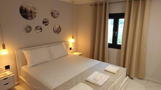 Un dormitorio con cama, mesitas de noche, decoración en la pared y una ventana con cortinas.