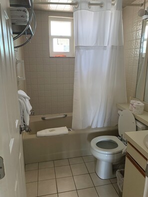 Ein Badezimmer mit Badewanne, Toilette und einem Fenster.