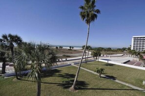 A hotel with a view of the beach, palm trees, and a parking lot. - Beachfront Condo at Treasure Island Beach Club (Treasure Island)