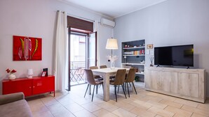 Ein modernes Wohnzimmer mit Essbereich, einem Fernseher und einem Bücherregal.