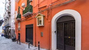 Eine schmale Straße mit einem Gebäude, das eine große Rundbogenöffnung, ein Fenster mit Blumen und ein Motorrad auf dem Bürgersteig zeigt.