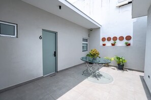 A modern outdoor patio with a glass table, potted plants, and a door marked with the number 6. - Loft a 15 min de Fundidora | Mundial 2026 (Monterrey)