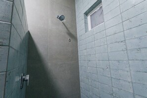 Une zone de douche carrelée avec une fenêtre et une porte.