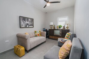 Un salon avec un canapé, une petite table, un téléviseur et une valise.