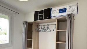 Een slaapkamer met een inbouwkast, een kledingrek en een bed.