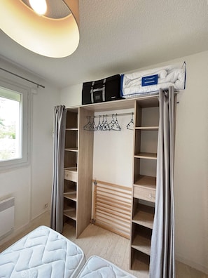Une chambre dotée d’une armoire intégrée, d’une tringle à vêtements et d’un lit.