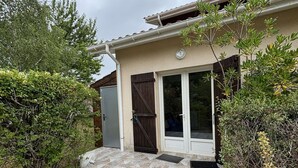 Een huis met een betegeld terras, een deur en een raam.