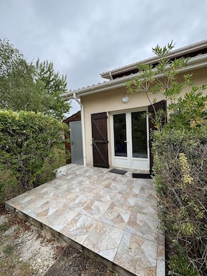 Une maison avec une terrasse carrelée, une porte et une fenêtre.