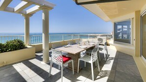 A terrace with a table and chairs, a view of the sea, and a building in the background. - CAPBRETON with ocean view, apartment for 6 people (CAPBRETON)