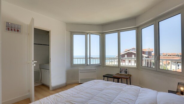 A bedroom with a large bed, a view of the sea, and a small table with a lamp. - CAPBRETON with ocean view, apartment for 6 people (CAPBRETON)