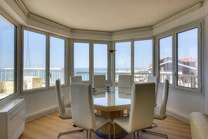 A corner room with a glass table and chairs, large windows with a view of the sea and buildings. - CAPBRETON with ocean view, apartment for 6 people (CAPBRETON)