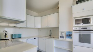 A modern kitchen with white cabinets, a microwave, an oven, and a toaster. - CAPBRETON with ocean view, apartment for 6 people (CAPBRETON)