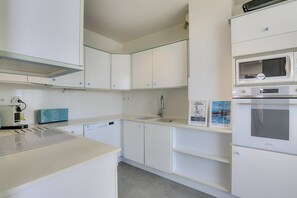 Uma cozinha moderna com armários brancos, micro-ondas, forno e torradeira.
