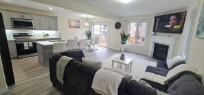 Una sala de estar moderna con un sofá, televisión, chimenea y balcón.