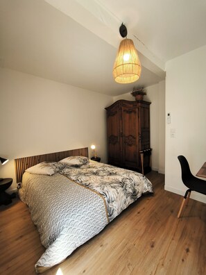 A bedroom with a bed, a wooden wardrobe, a desk with a chair, and a hanging light fixture. - New T2 30 m2 air-conditioned, private garden terrace, 10 mn from train station and town center. (Toulouse)