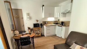 Una sala moderna con un sofá de cuero marrón, una mesa de centro de madera y un comedor con una mesa y sillas de madera.