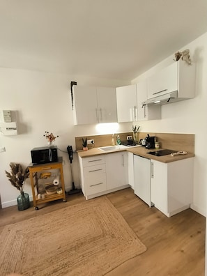 A compact kitchen with white cabinets, a wooden countertop, a built-in microwave, and a small sink. - New T2 30 m2 air-conditioned, private garden terrace, 10 mn from train station and town center. (Toulouse)