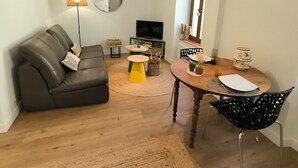 Una sala de estar con sofá, mesa de centro, televisor y un comedor con mesa y sillas.