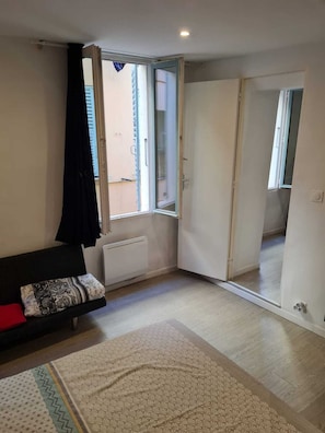 A room with a bed, a radiator, a window with curtains, and a sliding door. - Apartment in the heart of old Nice near the sea (Nice)