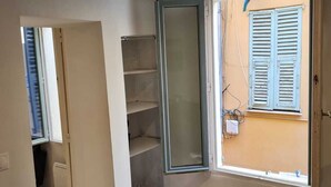Una stanza con una finestra, una porta e scaffali a muro.