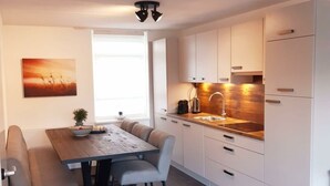 A modern kitchen with white cabinets, a wooden countertop, and a built-in sink. - Dijkhuis Sauna 6 (Medemblik)